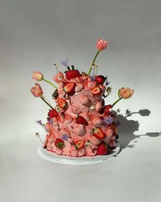 a pink cake with strawberries and flowers on it