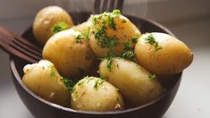 a wooden bowl filled with potatoes on top of a table