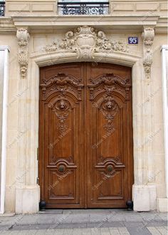 two large wooden doors sitting next to each other on the side of a stone building