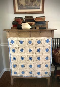 a crocheted blue and white afghan on a wooden table next to a chair