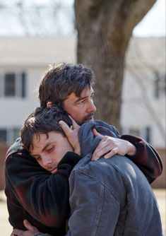 two men hugging each other in the street