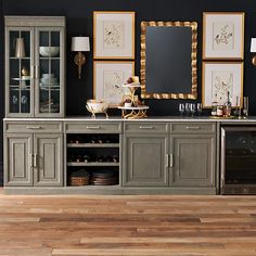 a dining room with black walls and wooden floors, gold framed pictures on the wall