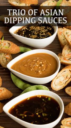 several small bowls filled with dipping sauce next to bread rolls on a wooden table top