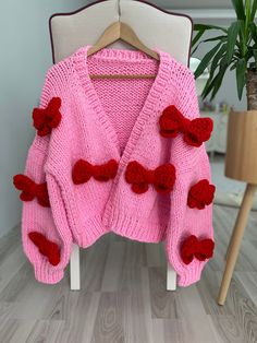 Big Red Bows Cardigan, Chunky Cropped Cardigan For Woman, Pink Sweater With Red Bows, Unique Gift For Women, Vintage, Handmade Our products are specially designed by our Mysisloops brand and are 100% original and 100% handmade. This carefully designed thick, soft art cardigan is made from a wool blend. The bow patterns on it are knitted with first-class  threads and sewn to the cardigan. All eyes will be on you and you will not want to take it off with this iconic wonderful design jacket that yo Red Knitted V-neck Outerwear, Red Knitted Winter Cardigan, Red Knitted Cardigan For Winter, Red Hand Knitted Long Sleeve Cardigan, Red Hand Knitted Winter Cardigan, Handmade Red Long Sleeve Cardigan, Handmade Red Outerwear For Fall, Handmade Red Winter Outerwear, Red Knitted Cardigan