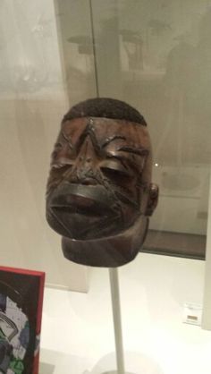 a wooden mask on display in a glass case