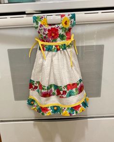 a dress hanging on the front of an oven with flowers and yellow ribbon around it