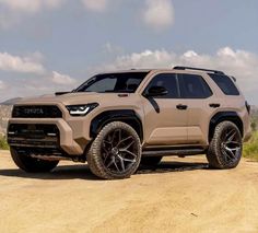 a tan toyota truck is parked on a dirt road