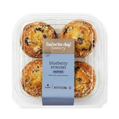 four blueberry muffins in a plastic container with a tag on the side