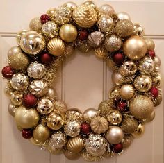 a christmas wreath hanging on the front door with ornaments all over it and red, white and gold balls