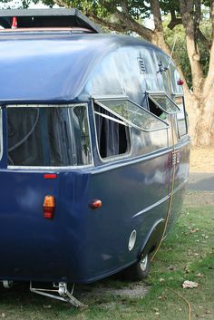 an old blue camper is parked in the grass