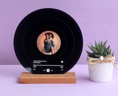 a small potted succulent next to a black and white photo frame on a wooden stand