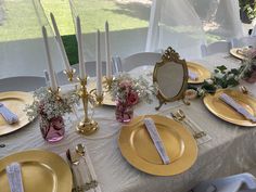 the table is set with gold plates and place settings