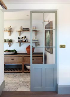 an open door leading to a kitchen with wooden cabinets and shelves on either side of it