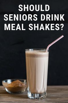 a glass filled with milk next to a bowl full of cereal and a straw in it