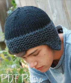 a young man wearing a knitted hat looks down at his cell phone in front of him