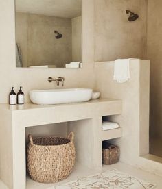 a bathroom with a sink, mirror and basket on the counter in front of it