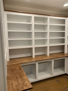 empty white bookcases in a room with wood flooring