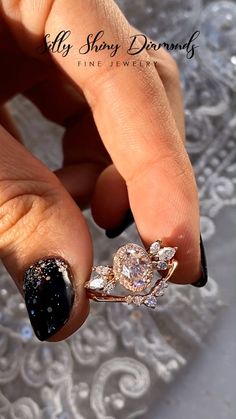 a woman's hand with black and white nail polish holding a diamond engagement ring