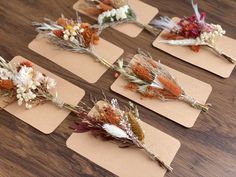 six dried flowers laid out on top of each other in different shapes and sizes, sitting on brown cards