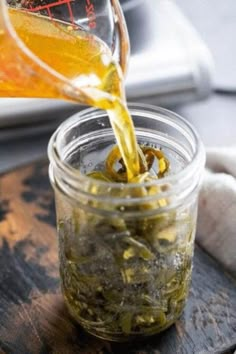 a person pouring tea into a glass jar