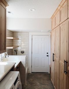 a washer and dryer in a small room with wooden cabinets on both sides