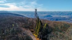 a radio tower sitting on top of a hill next to trees and hills in the background