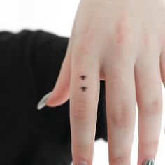 a woman's hand with a tiny tattoo on her left thumb and the ring finger