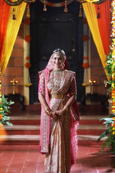 a woman in a bridal gown standing under an archway with flowers and garlands