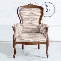 an upholstered chair sitting in front of a white brick wall