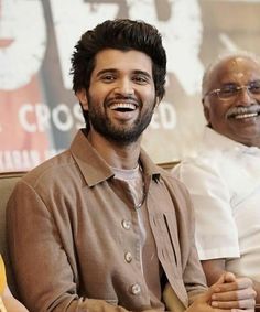 two men sitting next to each other smiling