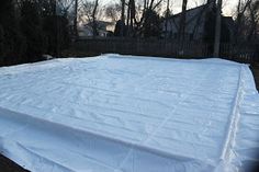 the tarp is covered with white fabric in front of a fence and house behind it