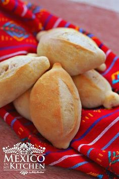 some bread rolls are sitting on a red and blue towel with colorful designs around them