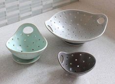 three bowls are sitting on the counter next to each other, one has holes in it