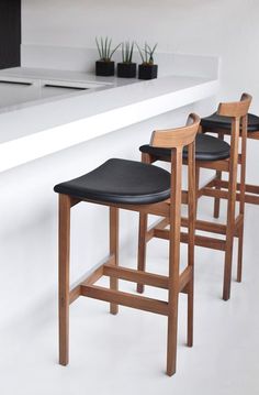 three wooden barstools sitting next to each other in front of a white counter