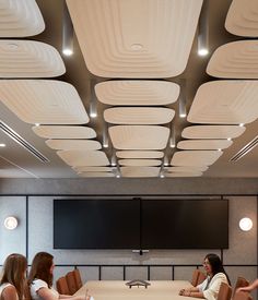 three women sitting at a conference table in front of a projector screen