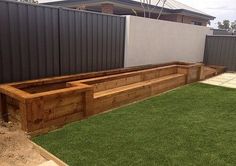 a wooden bench sitting in the middle of a grass covered yard next to a fence