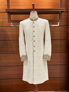 With this gorgeous white embroidered sherwani for men, you can really make a statement on your wedding day! It's a work of art! Beautiful embroidered floral patterns adorn the karandi base, and the ban and cuffs are embellished with hand-stitched zardozi designs. Various zari materials ensure a regal appearance by balancing the color scheme. At [Your Shop Name], we provide a made-to-measure experience while placing a premium on quality. For the ideal fit, be prepared for a measurement form and a Off White Nehru Jacket With Naqshi For Wedding, Cream Embroidered Sherwani For Ceremonial Occasions, Ceremonial Cream Embroidered Sherwani, White Nehru Jacket For Groom With Traditional Drape, White Nehru Jacket With Traditional Drape For Groom, White Nehru Jacket With Zari Work For Groom, Embroidered Off-white Bandhgala For Wedding, Embroidered Off White Bandhgala For Wedding, White Fitted Bandhgala With Resham Embroidery