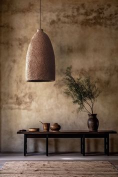 a table with two vases on it and a plant hanging from the ceiling above