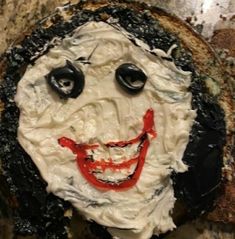 a face made out of bread with black eyes and red paint on it's face