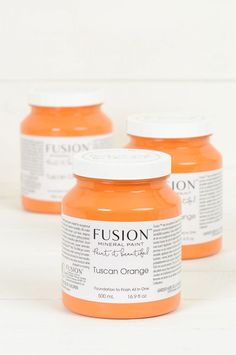 three jars of orange acrylic paint on a white background with the words fusion painted over them