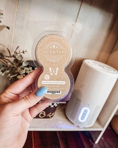 a person holding up an item in front of a wall mounted air purifier