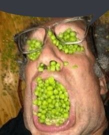 a man with green peas on his face and eyeglasses covering his eyes while looking at the camera