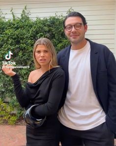 a man and woman standing next to each other in front of a house with the words tiktok on it