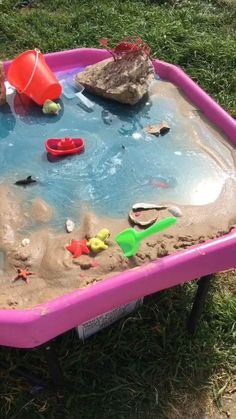 a child's sand and water play table with toys in it on the grass