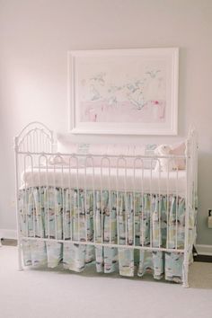 a white crib in a baby's room with a painting on the wall