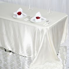 the table is set for two with white linens and red rose petals on it