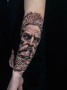 a man's arm with a black and grey tattoo on it