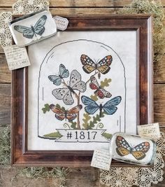 cross stitch kit with butterflies in frame and doily on wooden table next to it