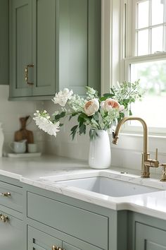 a white vase filled with flowers sitting on top of a kitchen counter next to a sink