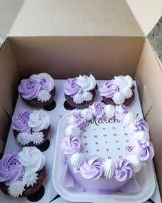 a box filled with lots of cupcakes covered in purple and white frosting